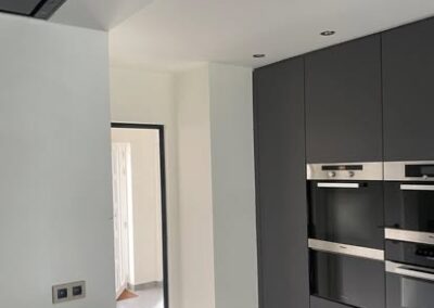 Strakke moderne keuken met donkere keukenkasten, ingebouwde toestellen en verzorgd schilderwerk.
