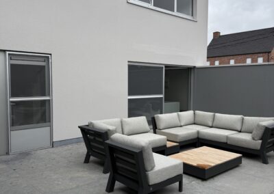Strakke buitengevel met verzorgde schilderafwerking en een modern terras met stijlvolle loungezetels.